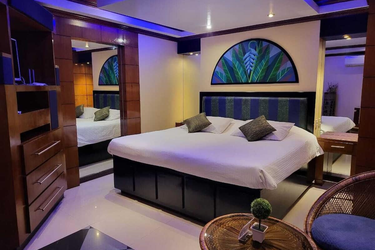 Quarto moderno com uma cama grande, um espelho e uma peça decorativa na parede.