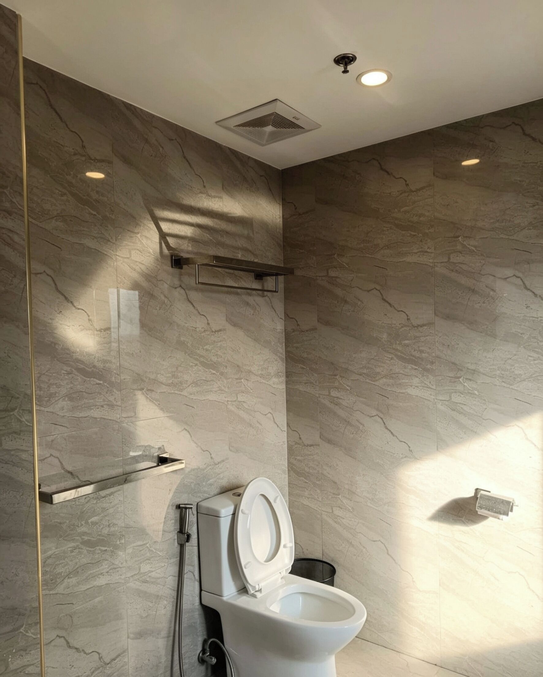 Une salle de bain moderne avec des toilettes, un espace douche et un mur en marbre.