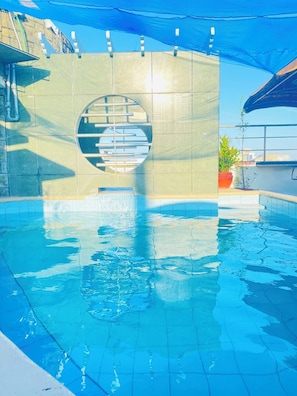 A swimming pool with a circular window, tiled walls, and a blue canopy overhead. - Fields Palace Hotel (Angeles City)