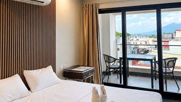 Habitació d'hotel amb llit, escriptori, cadira, aire condicionat i un balcó amb vistes.