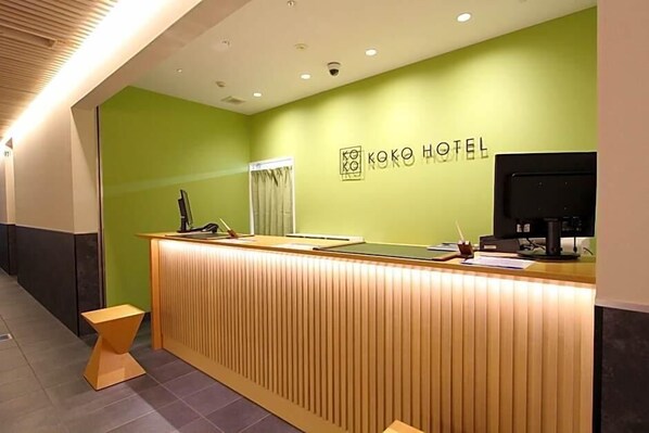 Una recepción con una pared verde y un cartel que dice 'KOKO HOTEL'.