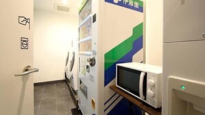 A hotel room with a washing machine, a microwave, and a door with a green and blue design.