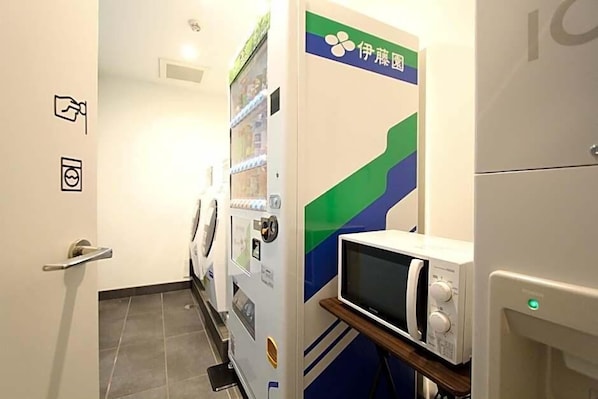 Ein Hotelzimmer mit Waschmaschine, Mikrowelle und einer Tür mit blaugrünem Dekor.