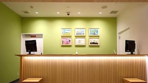 A reception area with a wooden counter, four framed artworks on the wall, and two black speakers on either side.