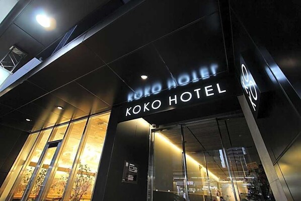 Exterior del hotel Koko, con fachada moderna y amplios ventanales de vidrio.