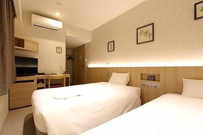Een hotelkamer met twee bedden, een bureau met stoel, een televisie en een wandairconditioner.