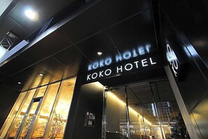 Het uiterlijk van Hotel Koko, met een moderne gevel en grote glasramen.