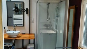 A compact bathroom with a sink, mirror, and shower.