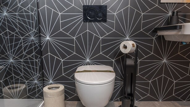 A modern bathroom with a geometric patterned wall, a toilet, a bidet, and a towel dispenser. - Ayamonte Trajano Suites - Ayamonte Centre (Ayamonte)