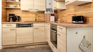 Una cocina moderna con armarios de madera, lavavajillas integrado, estufa y tostadora.