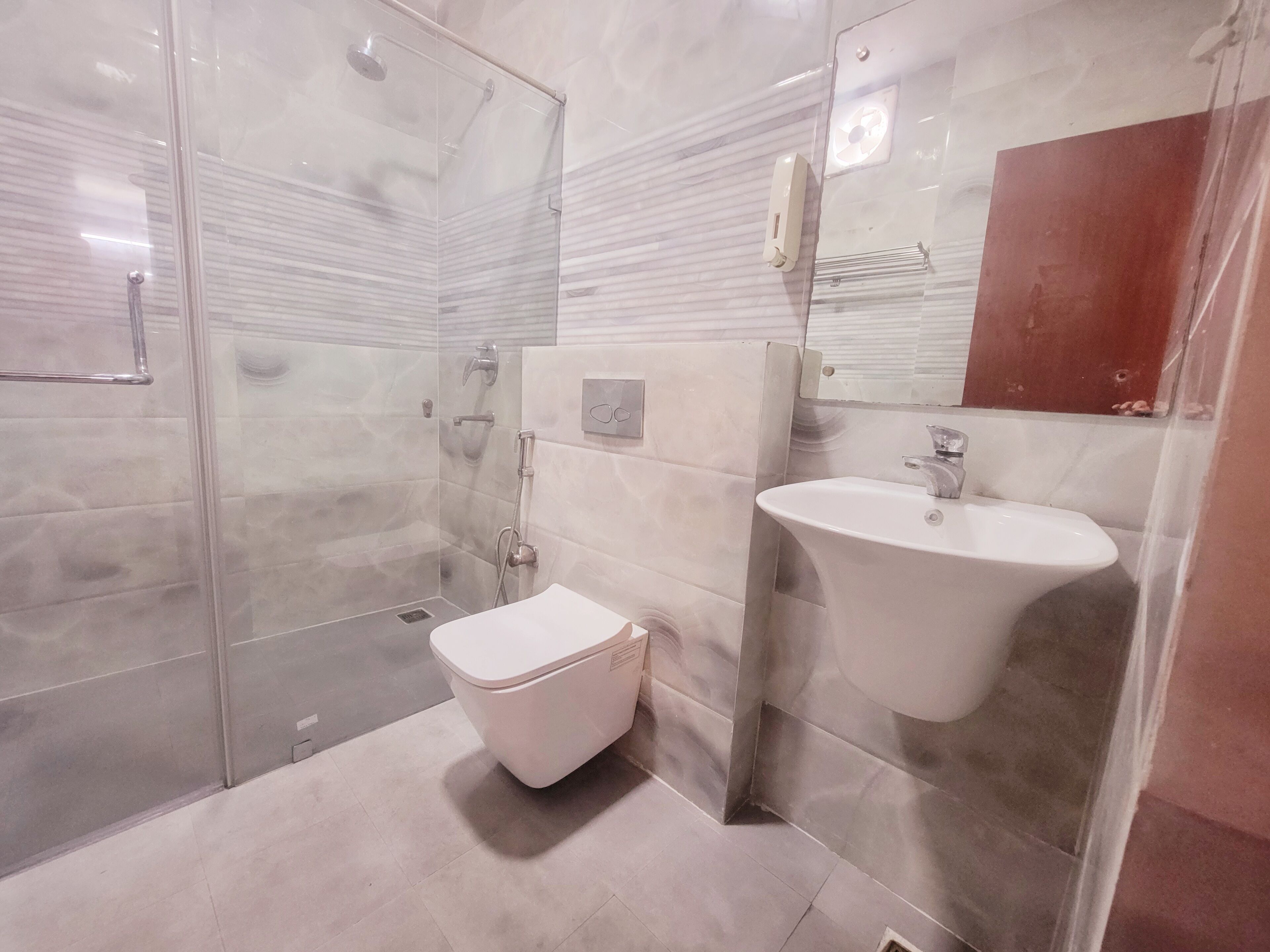 A modern bathroom with a glass shower enclosure, a white toilet, and a pedestal sink.