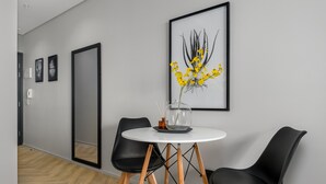 Et moderne spiseområde med et rundt bord, to sorte stole og et indrammet kunstværk på væggen.