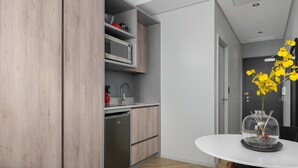 Et moderne køkken med indbygget mikrobølgeovn, opvaskemaskine og vask. Der er et spisebord med en klar glaskuppel i midten.
