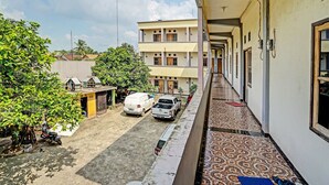 A corridor with a patterned floor, a parked white van, and a motorcycle. - OYO Life 90508 Wisma Kenanga (Palembang)
