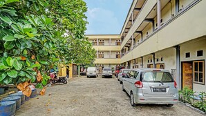 A courtyard with parked cars and a building with multiple floors and balconies. - OYO Life 90508 Wisma Kenanga (Palembang)