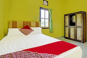 A bed with a red and white bedspread, a patterned pillow, and a window with a green curtain.