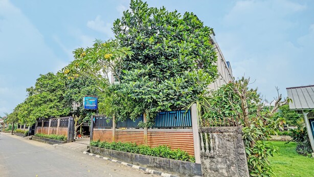 A building with a gated entrance, surrounded by greenery and a clear sky. - OYO Life 90508 Wisma Kenanga (Palembang)