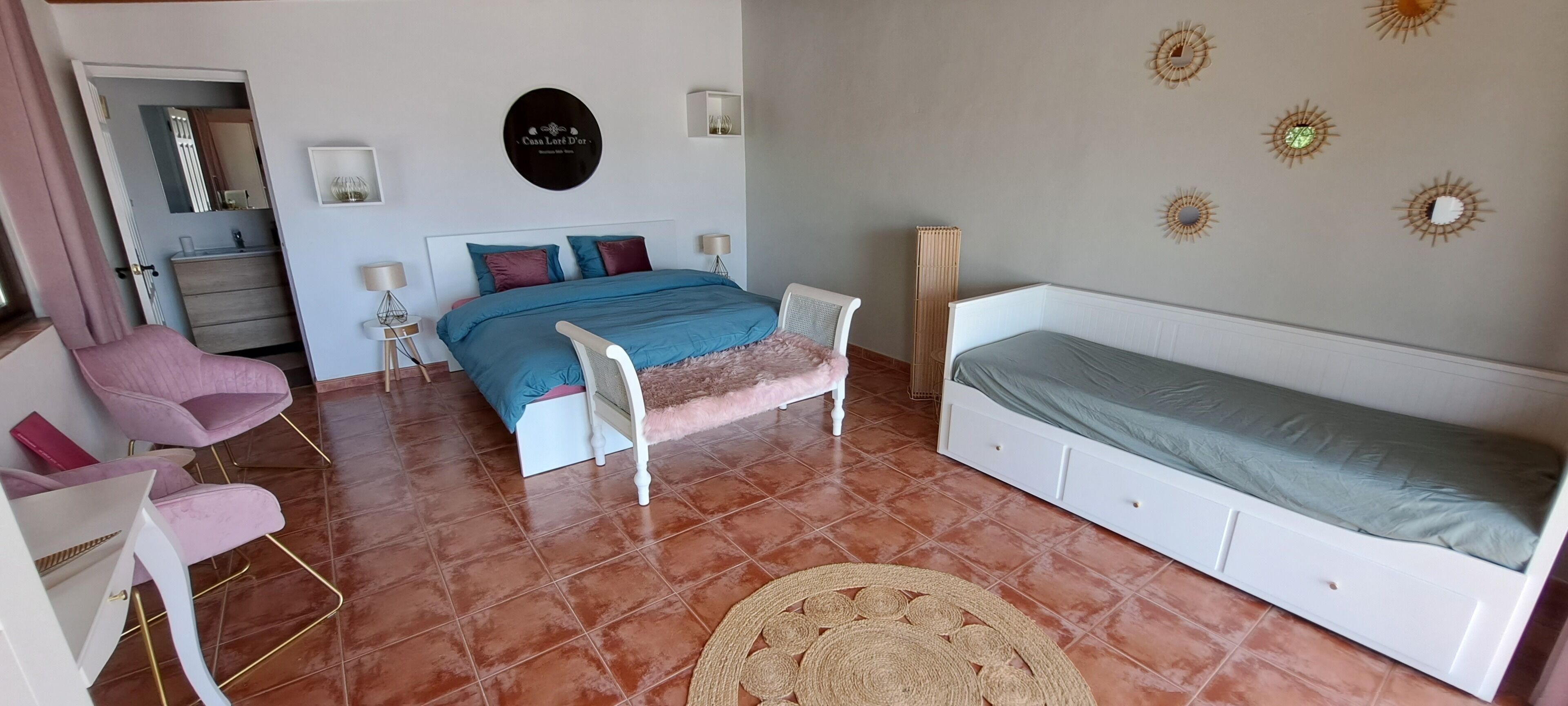 A bedroom with a bed, a chair, a bedside table, and a wall-mounted decoration.