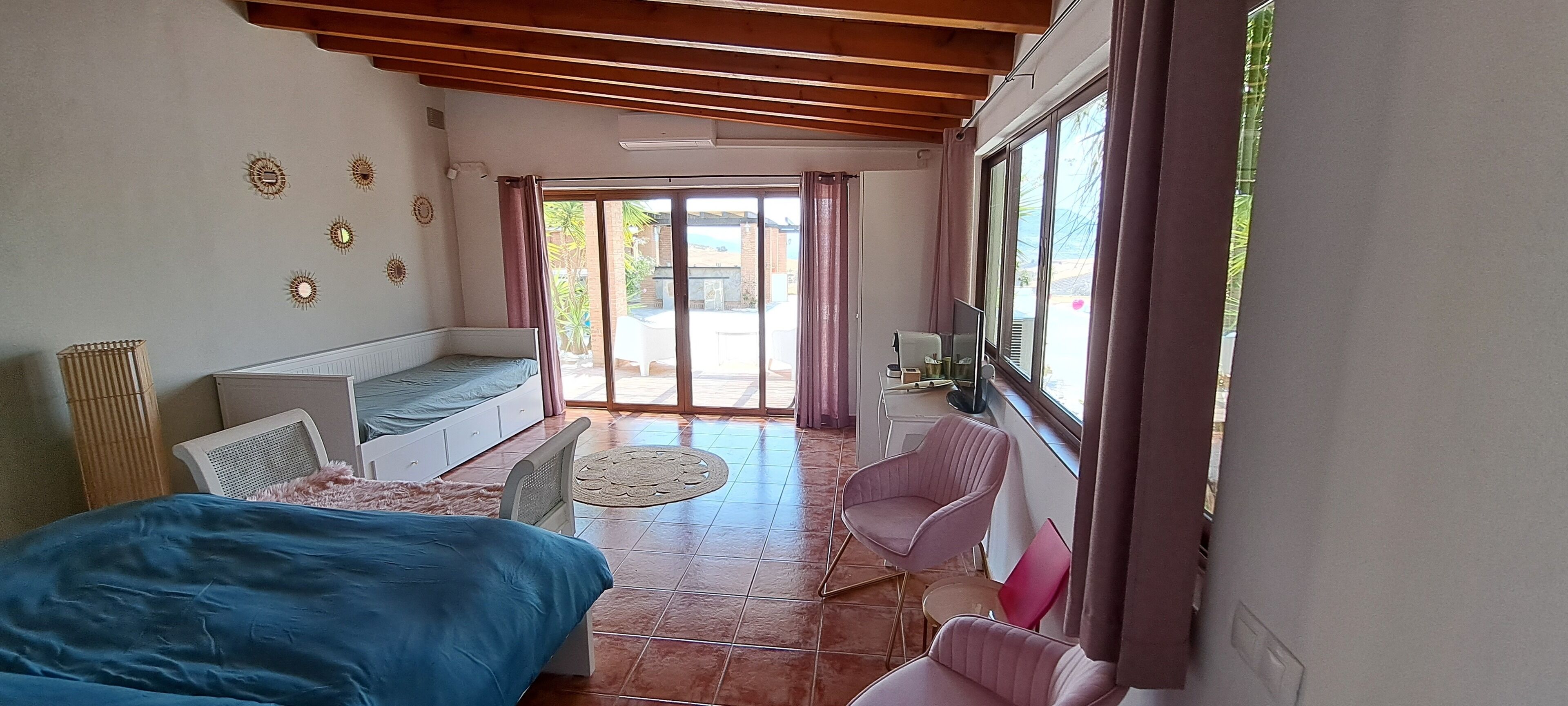 A bedroom with a bed, a seating area with a table, and a window with curtains.