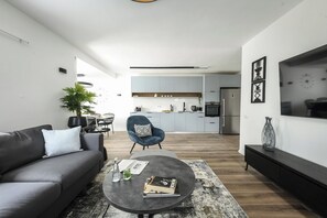 Ein modernes Wohnzimmer mit einer Couch, einem Couchtisch und einem Essbereich im Hintergrund.