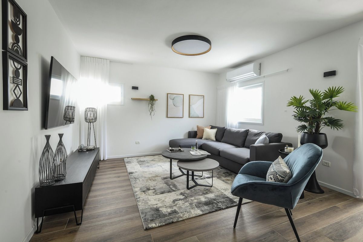 Un salon moderne avec un canapé, une table basse, une table d’appoint et une plante en pot.