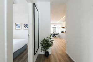 Ein Flur mit einem Bett, einer Zimmerpflanze und einem Essbereich im Hintergrund.