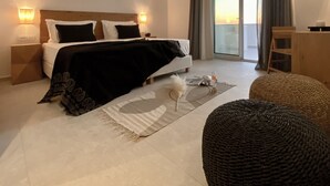A modern bedroom with a large bed, a desk, and a balcony view. - Calistus Mykonos (Mykonos)