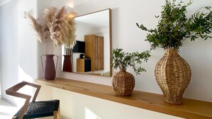 A modern living room with a wooden console table, a mirror, and two large woven vases with plants. - Calistus Mykonos (Mykonos)