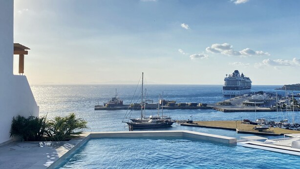 A pool area with a view of the sea and a cruise ship in the background. - Calistus Mykonos (Mykonos)