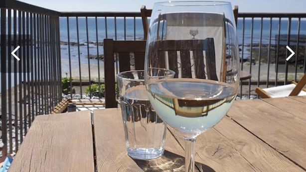 A wooden table with two glasses of white wine and a view of the ocean. - Torpoint - Apartment - Sleeps4 - Seaside - Parking (Torpoint)