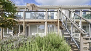 A two-story building with a balcony, outdoor seating, and a staircase. - Torpoint - Apartment - Sleeps4 - Seaside - Parking (Torpoint)