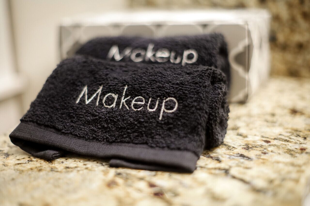 A black towel with the word "Makeup" on it, placed on a granite countertop.