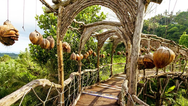 A wooden bridge with rope netting, surrounded by lush greenery and hanging coconuts. - Maha Gangga Valley by ecommerceloka (Karangasem)