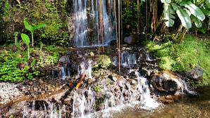 A waterfall surrounded by lush greenery and rocks. - Maha Gangga Valley by ecommerceloka (Karangasem)
