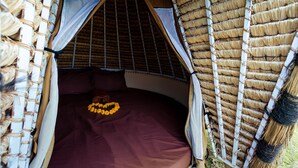 A bed with a brown mattress, a white sheet, and a decorative yellow flower arrangement. - Maha Gangga Valley by ecommerceloka (Karangasem)