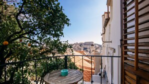 A balcony with a table and chairs, overlooking a cityscape with buildings and a hill. - Secret Orange by DuHomes (Dubrovnik)