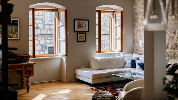 A cozy living room with a white sofa, wooden floor, stone wall, and large windows. - Secret Orange by DuHomes (Dubrovnik)
