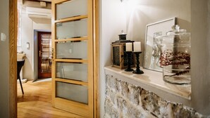 A hallway with a wooden door, a stone wall, and a shelf with decorative items. - Secret Orange by DuHomes (Dubrovnik)