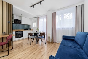 A modern living room with a blue sofa, wooden dining table, and chairs.