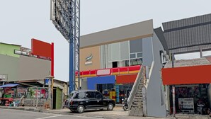 A street view with a building that has a large sign, a staircase leading to the entrance, and a parked car. - Hotel O Cihampelas Near Ciwalk Formerly D'River Guest House (Bandung)