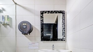 A small, compact bathroom with a toilet, sink, and a mirror with a black frame. - Hotel O Cihampelas Near Ciwalk Formerly D'River Guest House (Bandung)