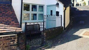 A white building with a sign reading "SEVERN BANK" and a blue door. - Cottagesleeps2-fireplace-valleyview-patio-garden (Telford)