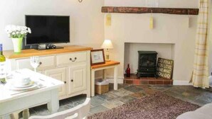 A cozy living room with a television, a fireplace, and a dining area. - Cottagesleeps2-fireplace-valleyview-patio-garden (Telford)