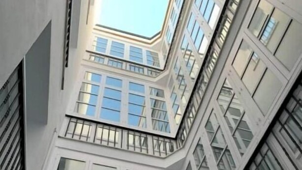 Un edificio alto con varios balcones y amplias ventanas.