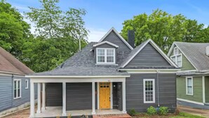 A residential house with a front porch, a garage, and a small front yard. - Modern Memphis Game House, Hot Tub! Close to Beale (Memphis)
