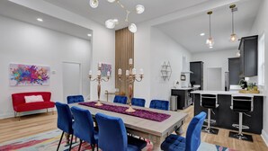 A modern kitchen with a central island, a dining area with blue chairs, and a red sofa. - Modern Memphis Game House, Hot Tub! Close to Beale (Memphis)