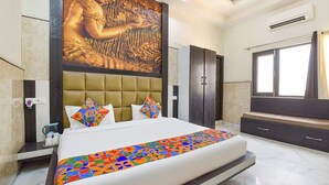 A modern hotel room with a large bed, a headboard with a geometric pattern, a wall-mounted TV, and a large window with curtains. - Fabhotel Prime Shubh ISBT (Dehradun)