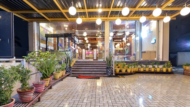 A spacious indoor area with a tiled floor, potted plants, and a staircase leading to upper levels. - Fabhotel Prime Shubh ISBT (Dehradun)