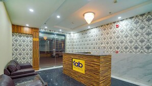 A reception area with a wooden reception desk, leather sofas, and patterned wallpaper. - Fabhotel Hc Mohali Inn (Mohali)