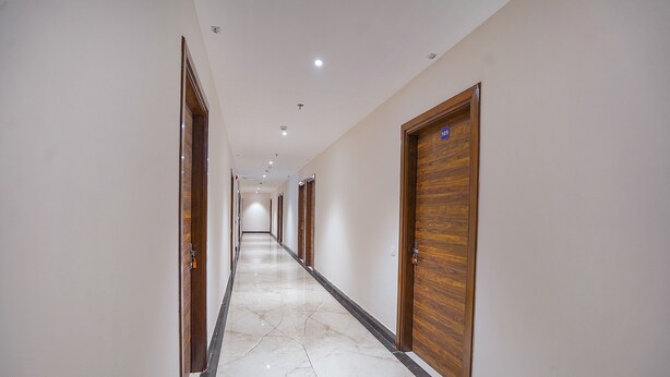 A long, narrow hallway with wooden doors on both sides, leading to individual rooms. - Fabhotel Hc Mohali Inn (Mohali)